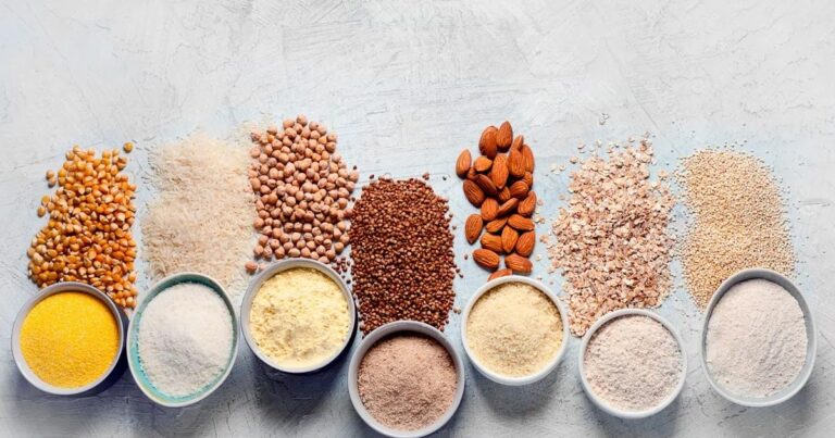 Variedad de harinas sin gluten: avena, algarroba y almendras en bowls sobre una mesa.