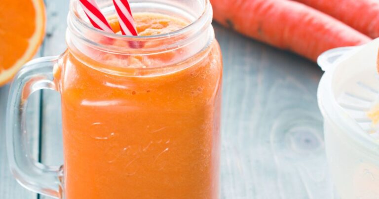 Vaso con licuado color morado, junto a ingredientes como arándanos, nueces, cacao en polvo y leche vegetal.