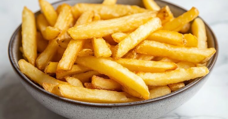 Papas fritas doradas y crocantes en un plato, ilustrando el resultado de la técnica con vinagre.