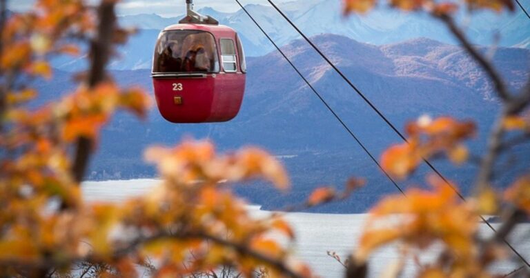 Vista aérea de las góndolas rojas del Teleférico Cerro Otto ascendiendo hacia la montaña en Bariloche.